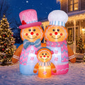 Inflatable pink gingerbread family in chef and Santa hats beside a Christmas tree